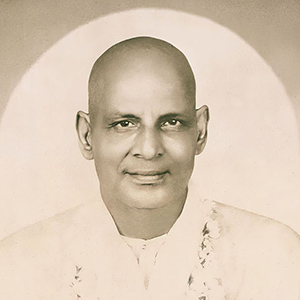 Swami Sivananda sitting in mediation with eyes open. 