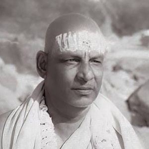 Sivananda sitting in contemplation with eyes open by the Ganges