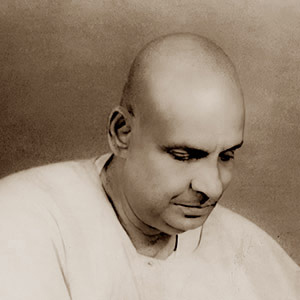 Swami Sivananda with pen in hand, writing.