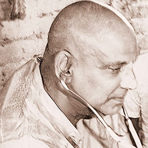 Sivananda uses a stethoscople to listen to the heart and lungs of an older wandering mendicant. 