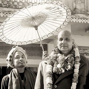 Swami Venkatesananda holding the umbrella over the head of his guru, Swami Sivananda