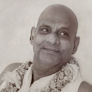 A candid smile from Swami Sivananda sitting in chair. 